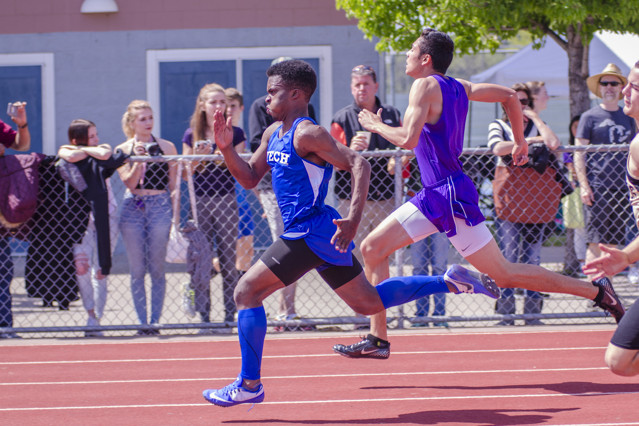 Athlete prepares for pole vault on a track with others watching.