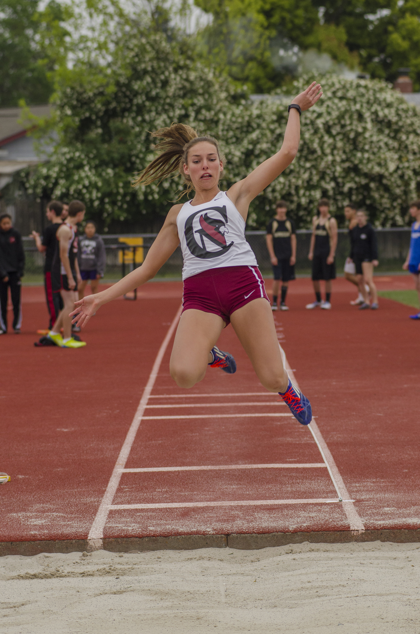 Athlete prepares for pole vault on a track with others watching.