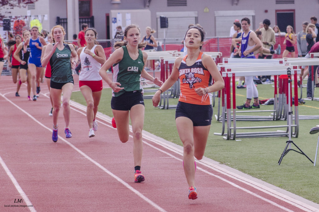 Athlete prepares for pole vault on a track with others watching.
