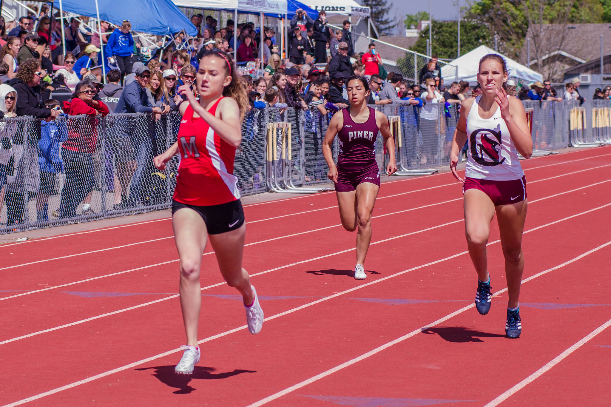 Athlete prepares for pole vault on a track with others watching.
