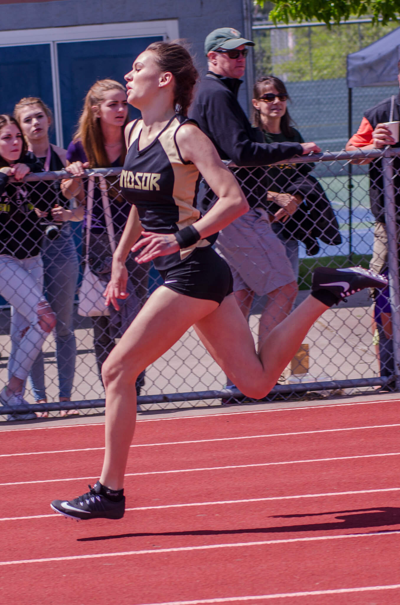 Athlete prepares for pole vault on a track with others watching.