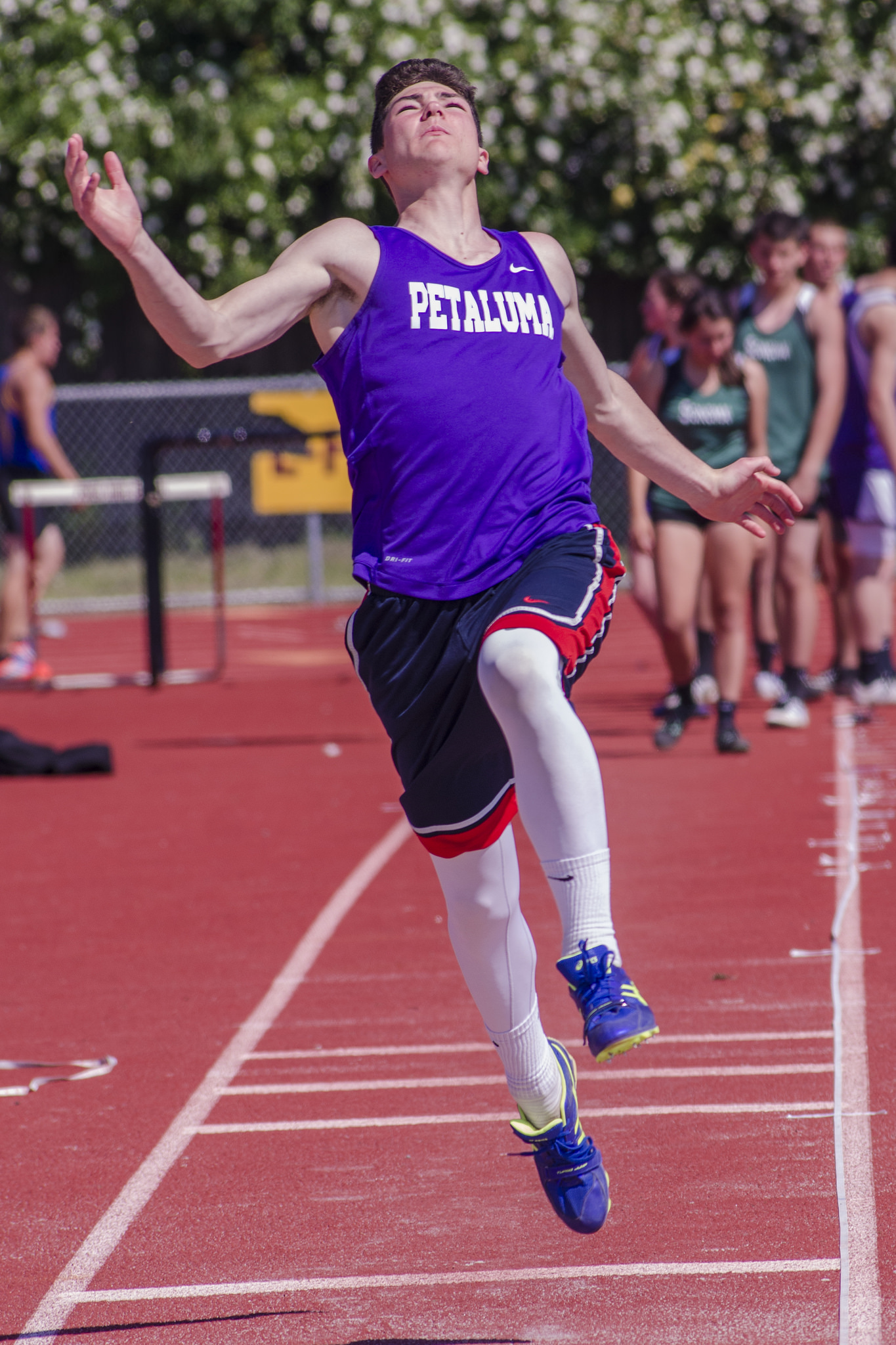 Athlete prepares for pole vault on a track with others watching.