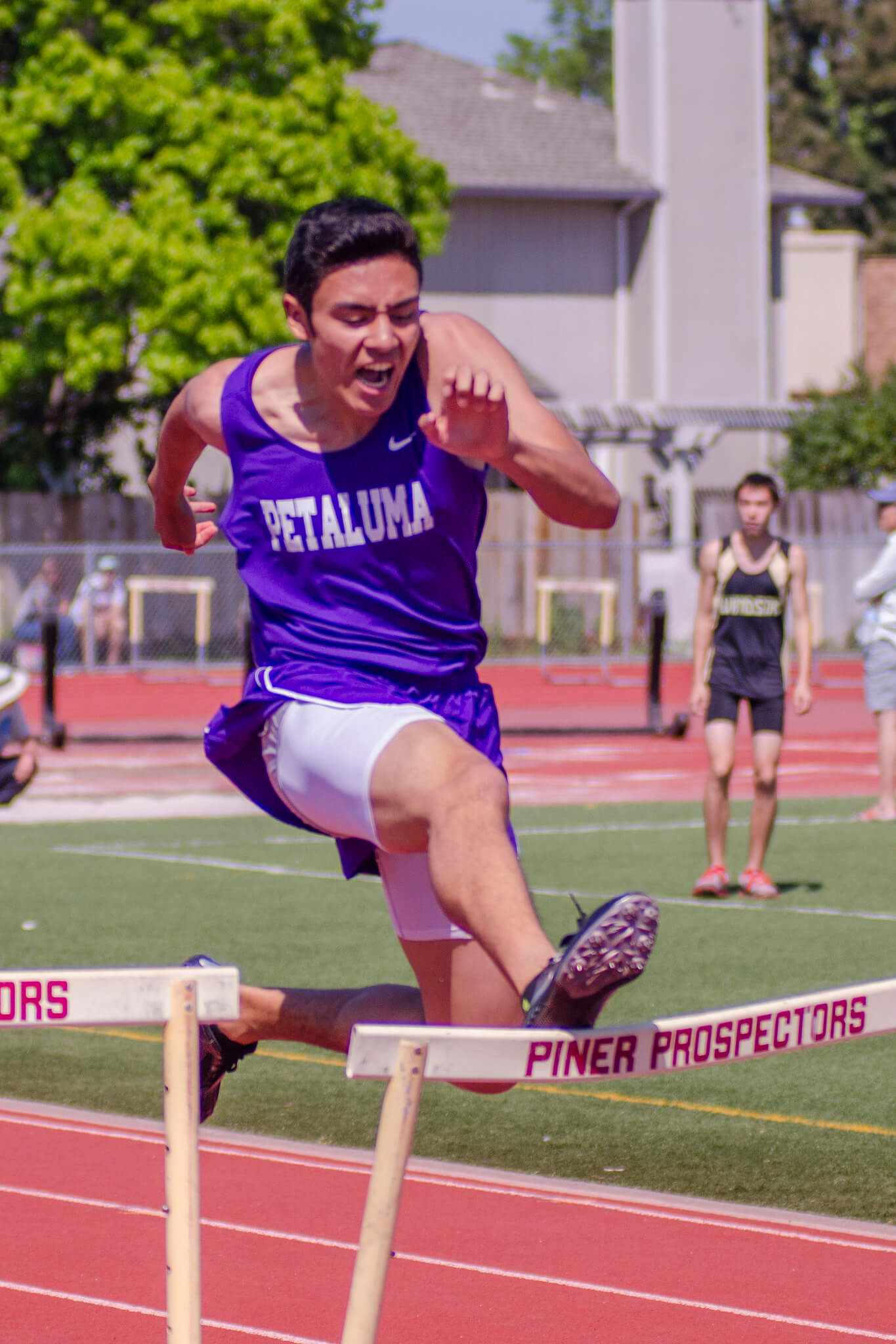 Athlete prepares for pole vault on a track with others watching.