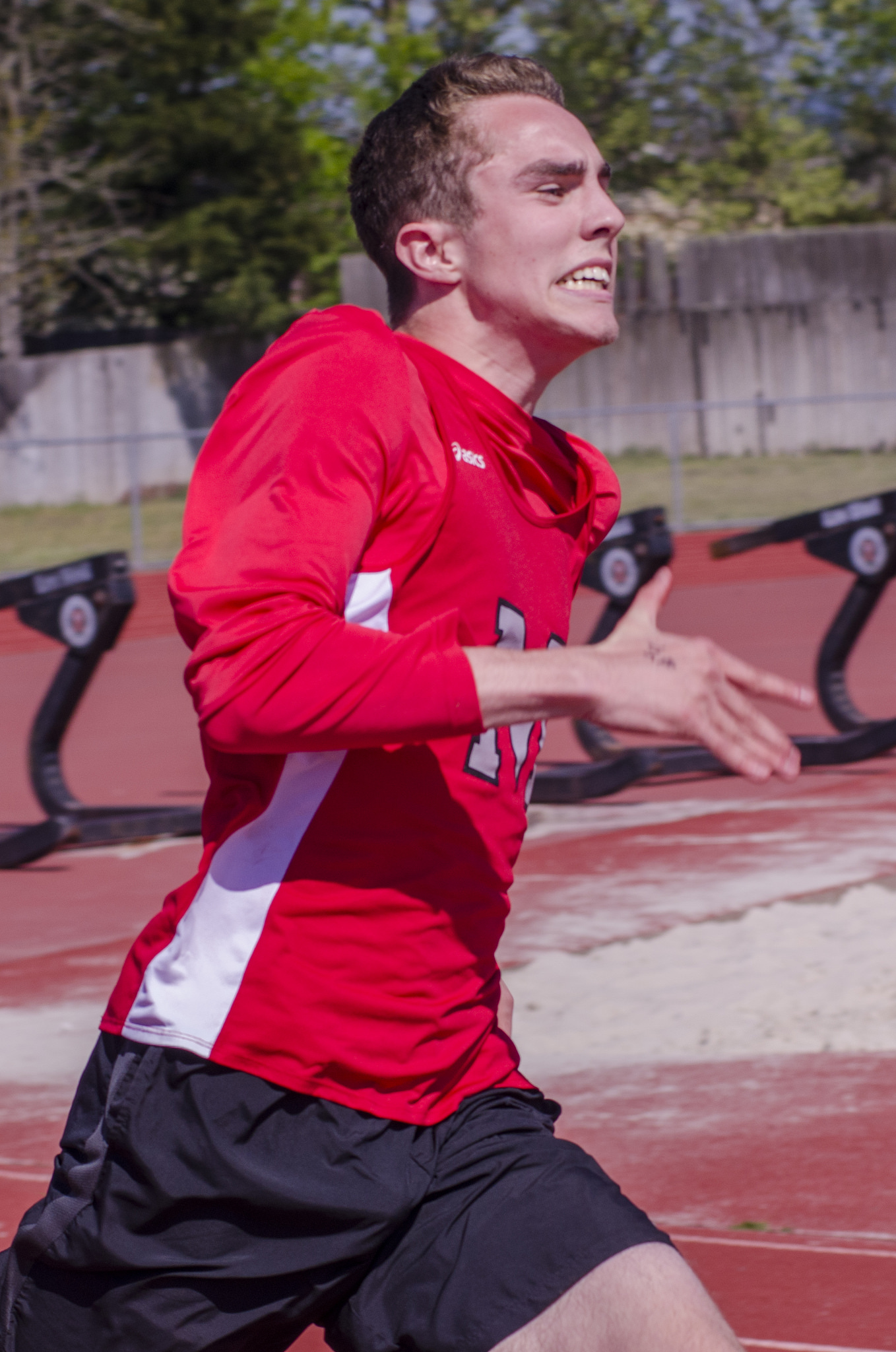 Athlete prepares for pole vault on a track with others watching.