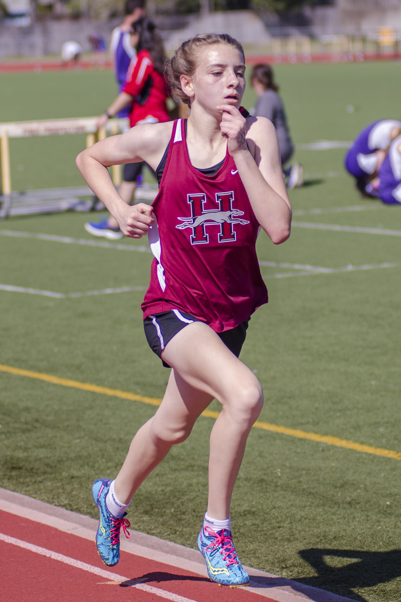 Athlete prepares for pole vault on a track with others watching.