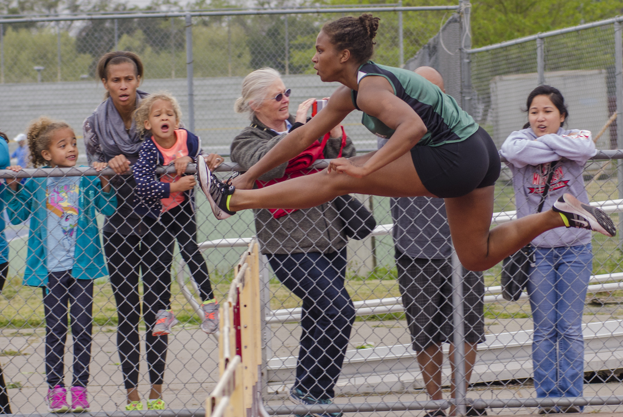 Athlete prepares for pole vault on a track with others watching.