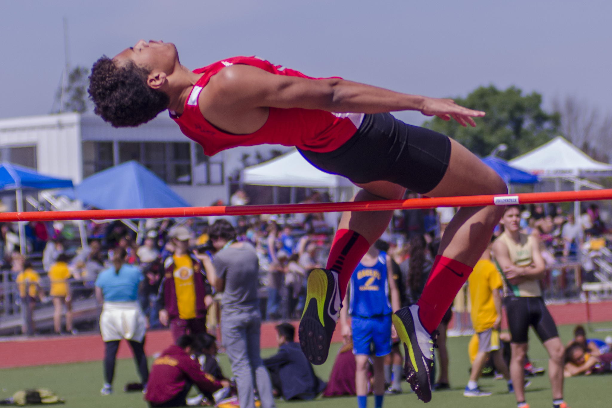 Athlete prepares for pole vault on a track with others watching.