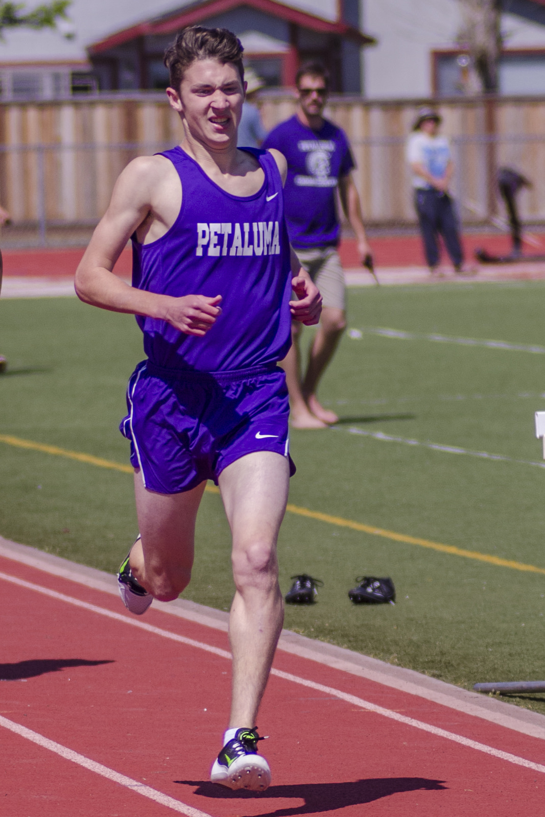Athlete prepares for pole vault on a track with others watching.