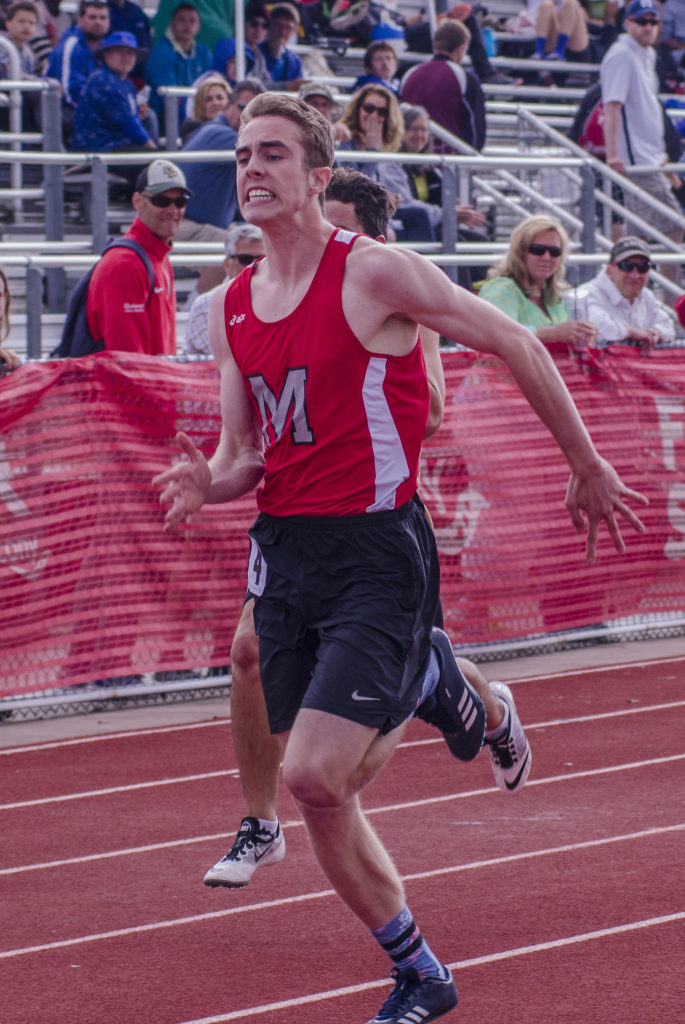 Athlete prepares for pole vault on a track with others watching.