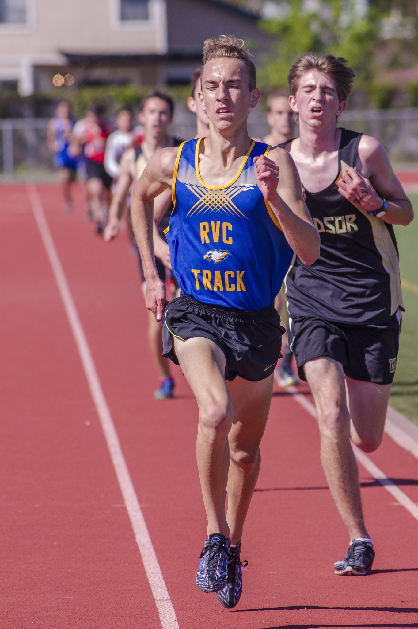Athlete prepares for pole vault on a track with others watching.
