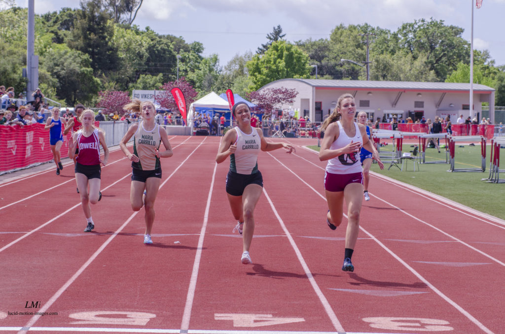 Athlete prepares for pole vault on a track with others watching.