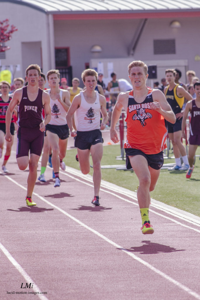 Athlete prepares for pole vault on a track with others watching.