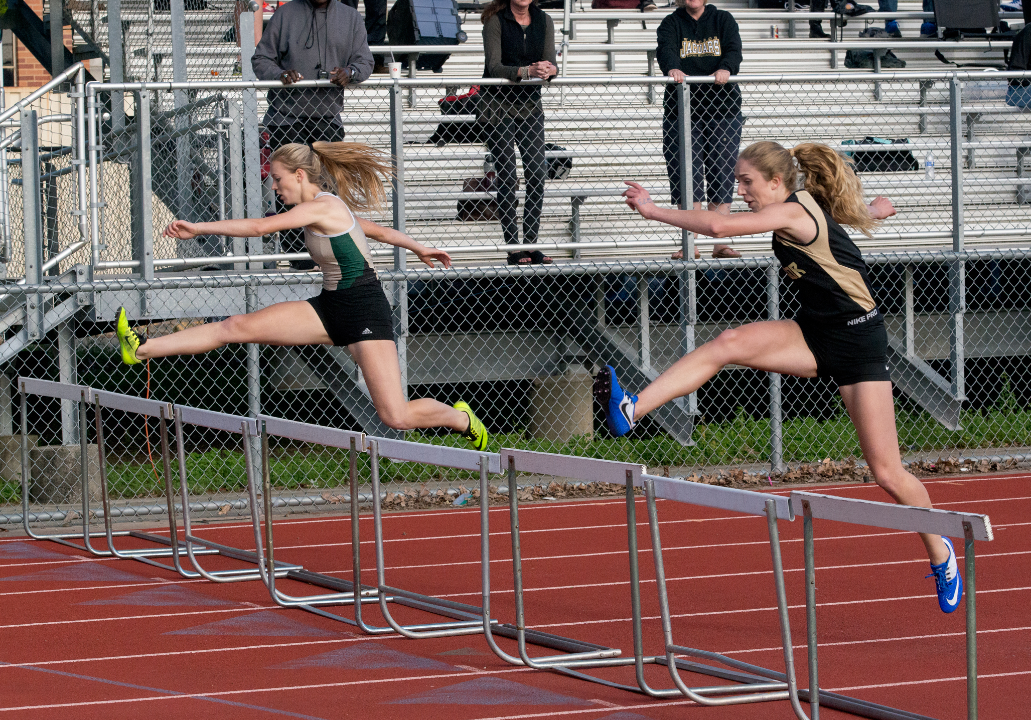 Athlete prepares for pole vault on a track with others watching.