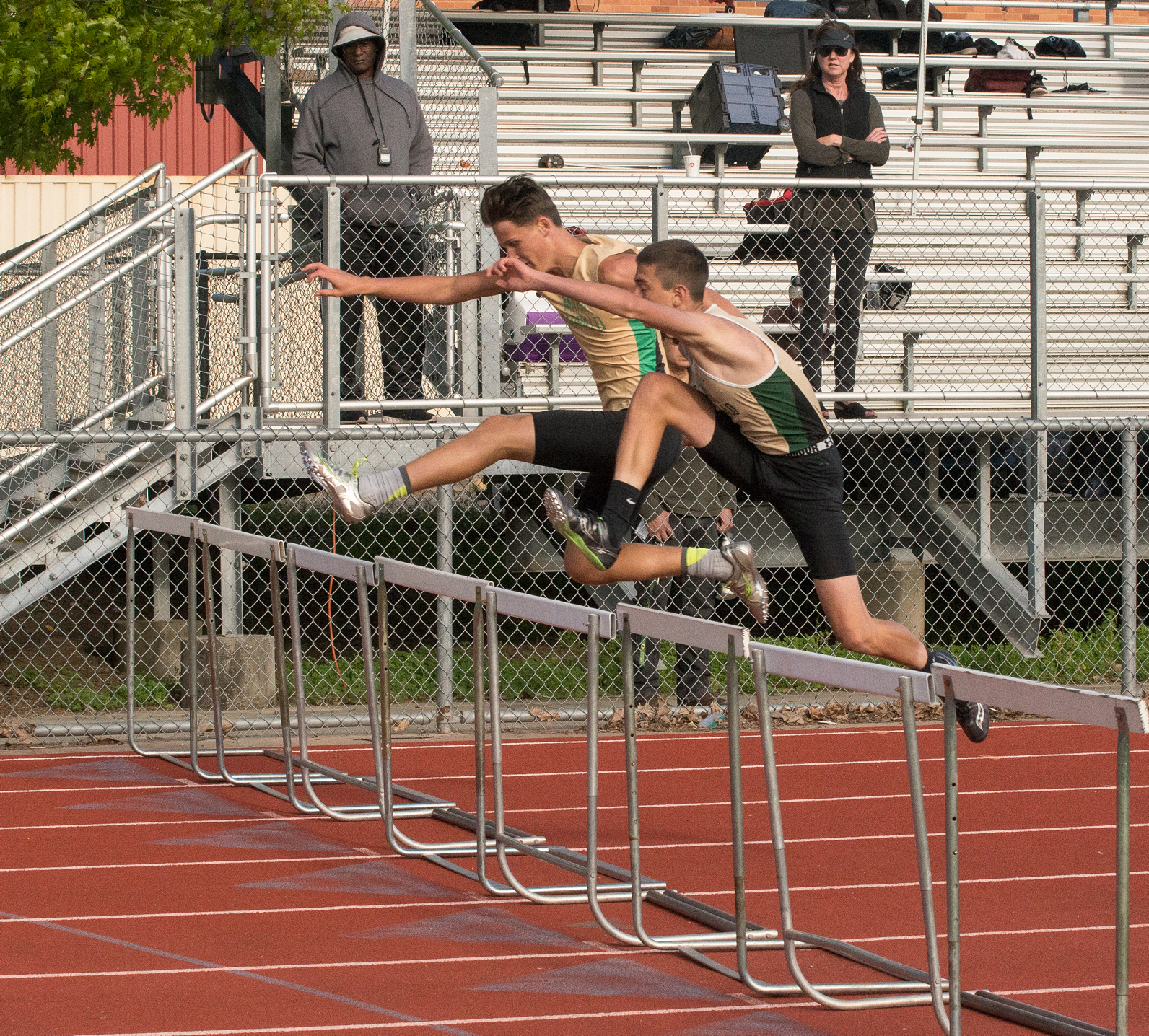Athlete prepares for pole vault on a track with others watching.