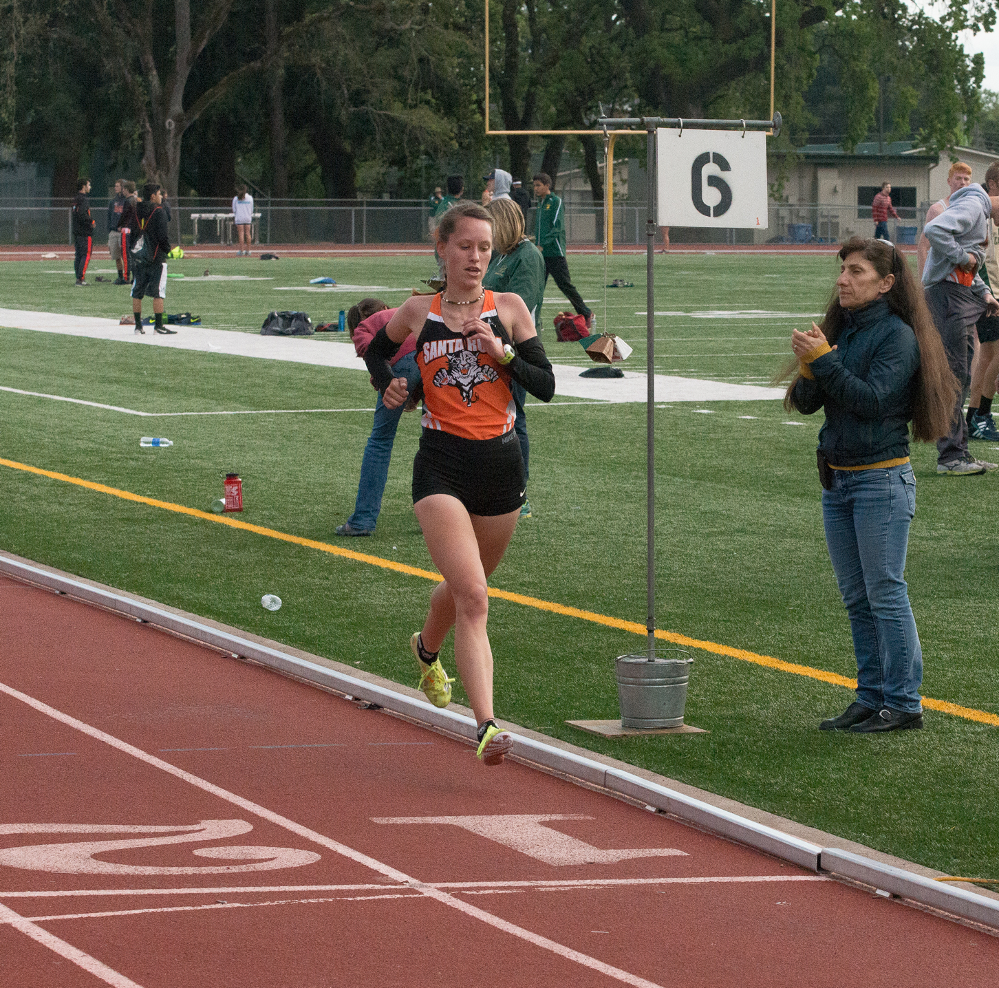 Athlete prepares for pole vault on a track with others watching.