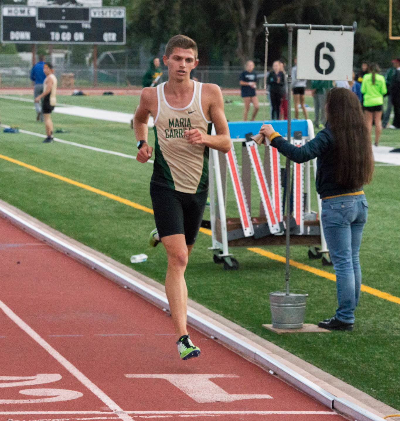 Athlete prepares for pole vault on a track with others watching.