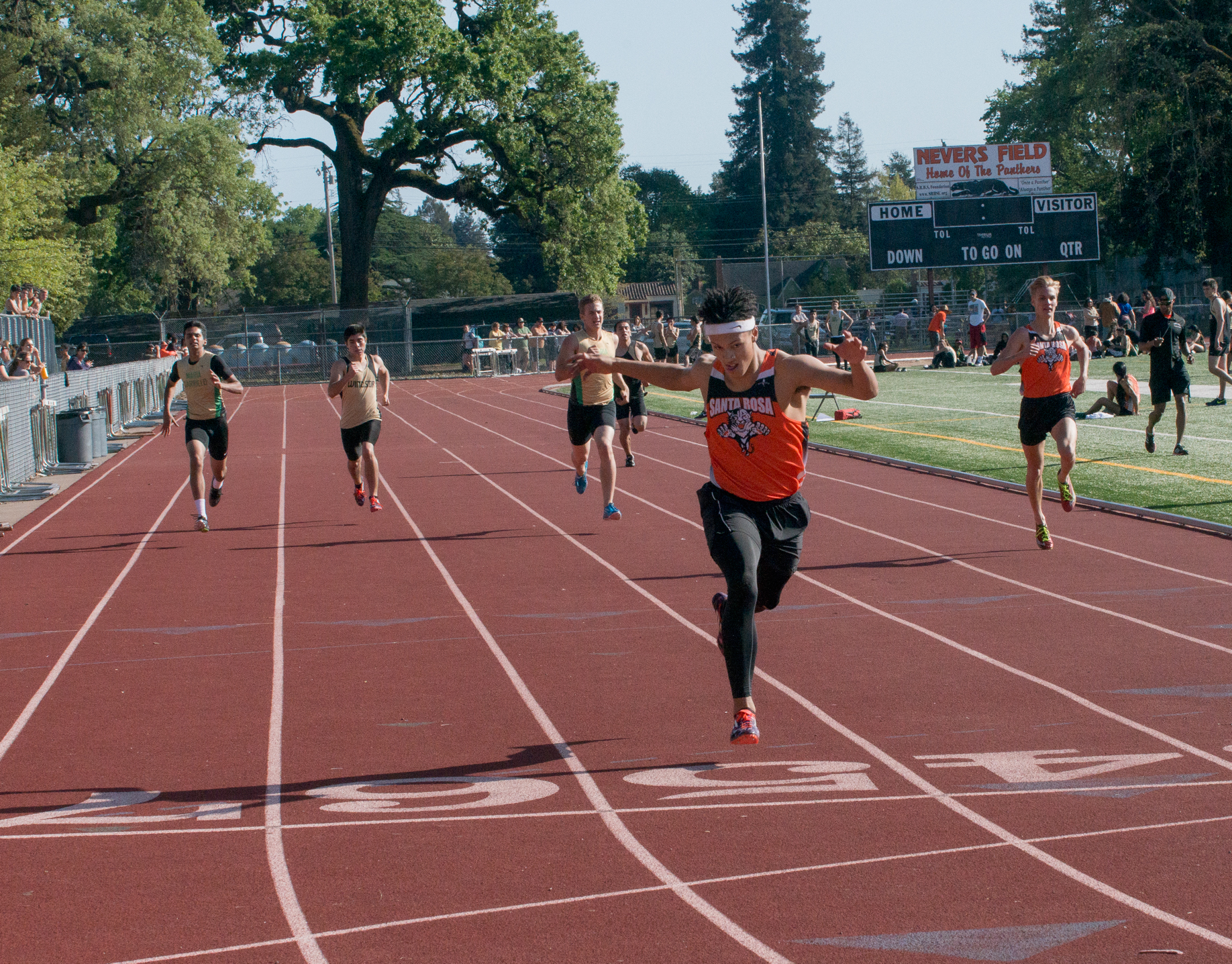 Athlete prepares for pole vault on a track with others watching.