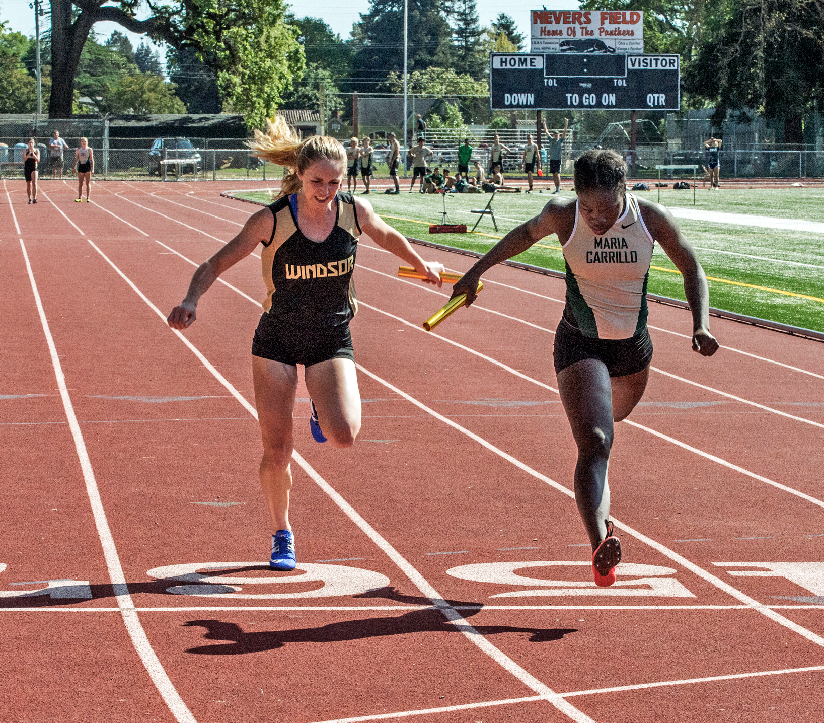 Athlete prepares for pole vault on a track with others watching.