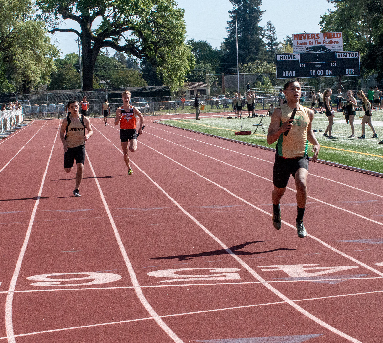 Athlete prepares for pole vault on a track with others watching.