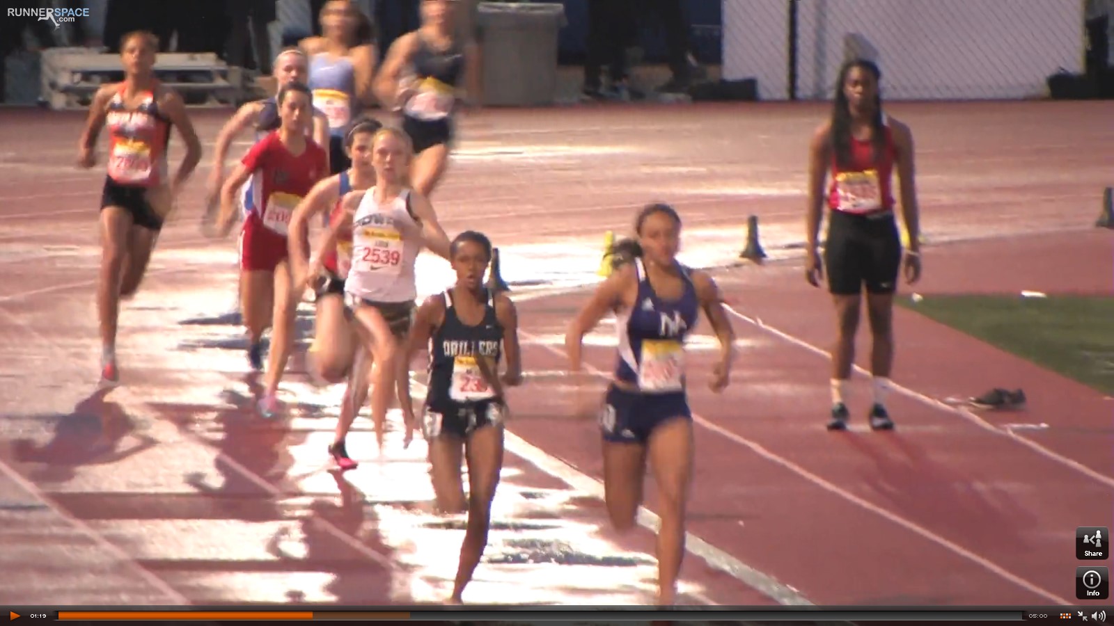 Athlete prepares for pole vault on a track with others watching.