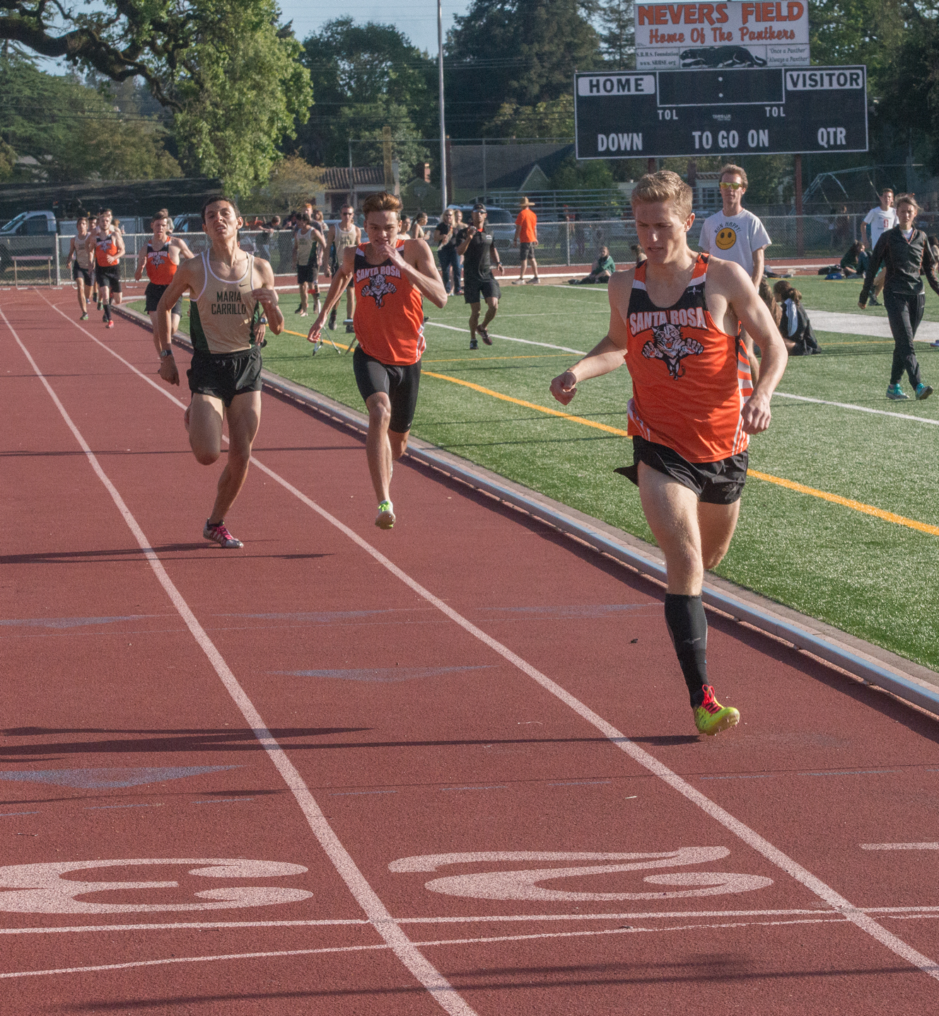 Athlete prepares for pole vault on a track with others watching.
