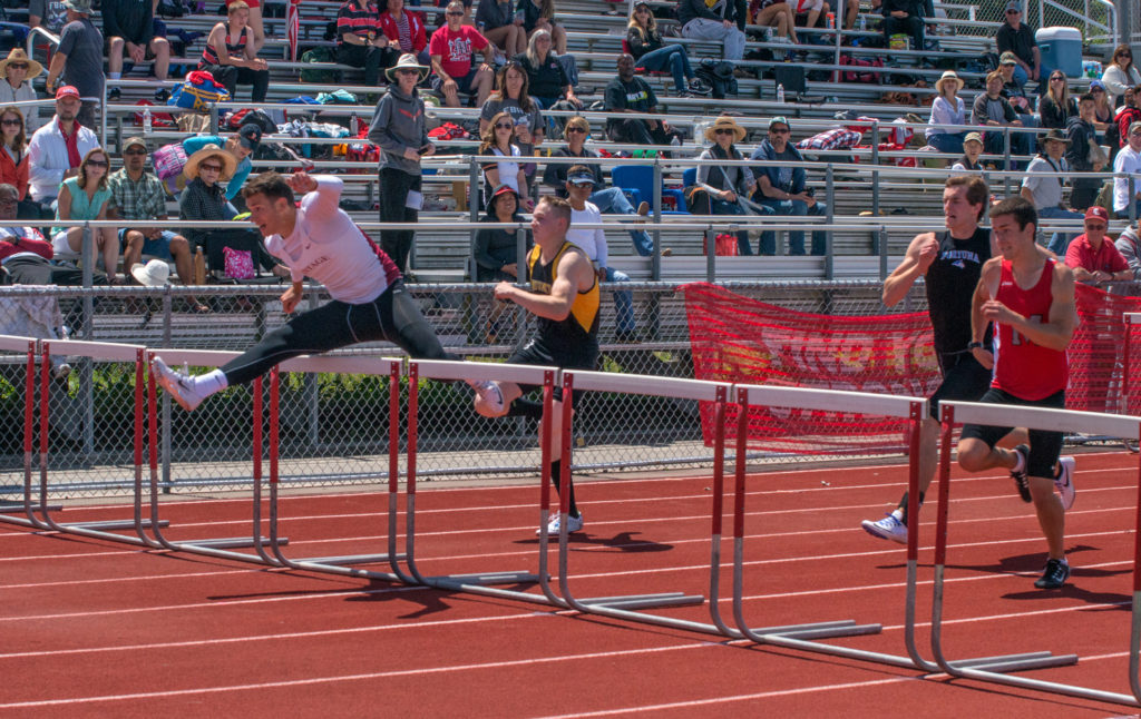 Athlete prepares for pole vault on a track with others watching.