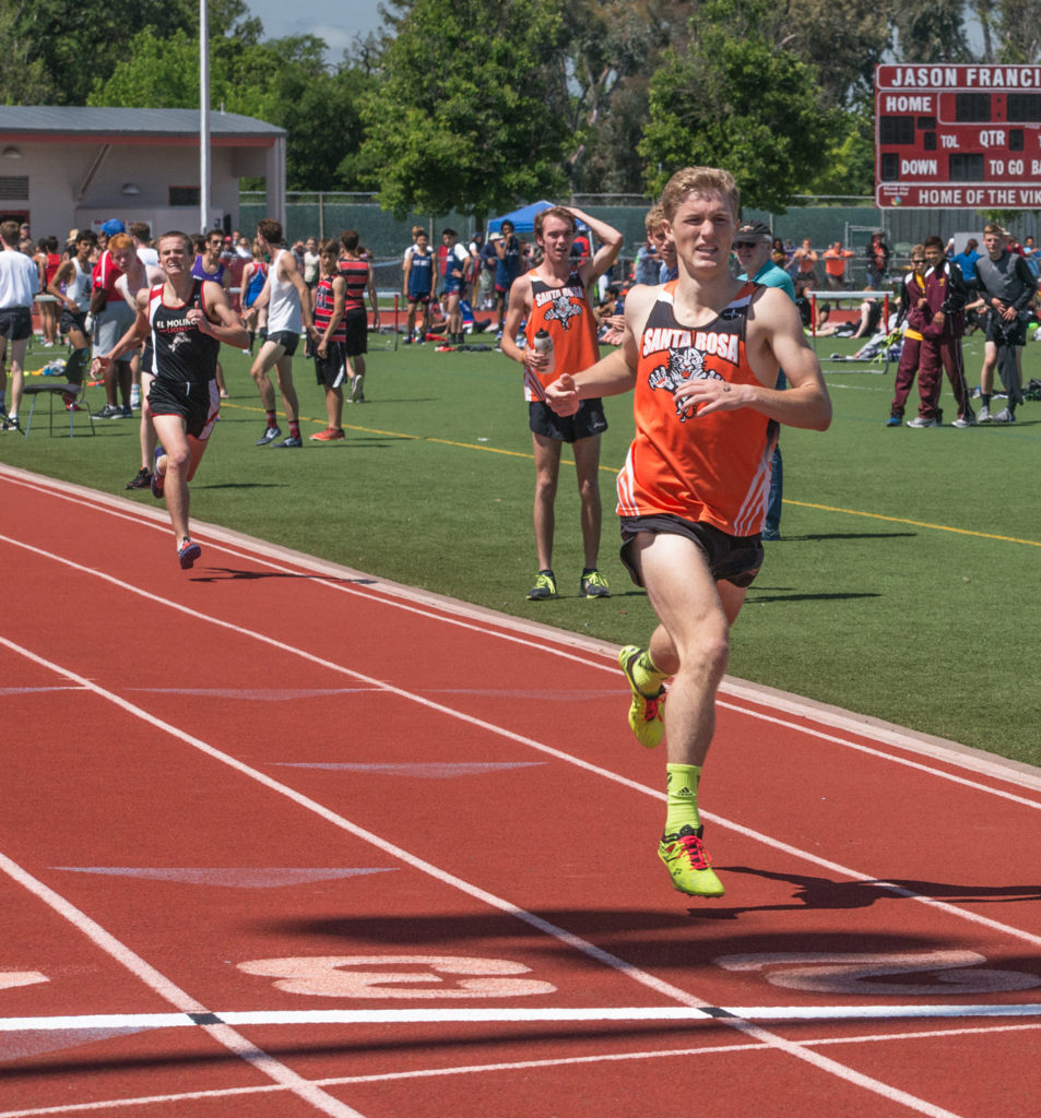 Athlete prepares for pole vault on a track with others watching.