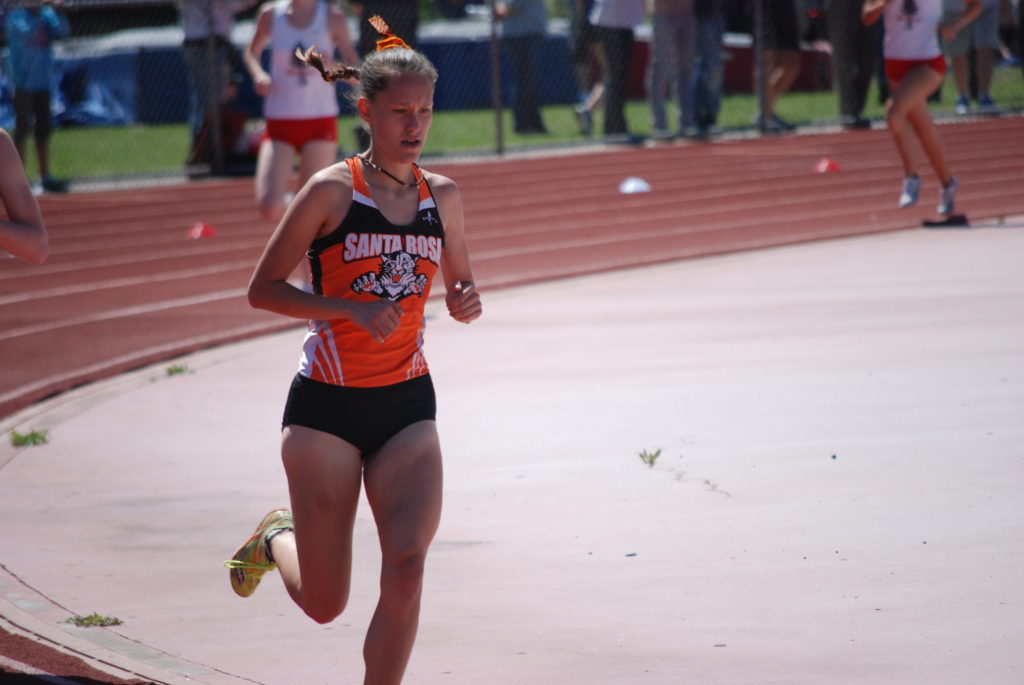 Athlete prepares for pole vault on a track with others watching.