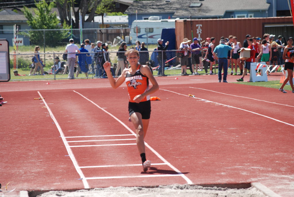 Athlete prepares for pole vault on a track with others watching.