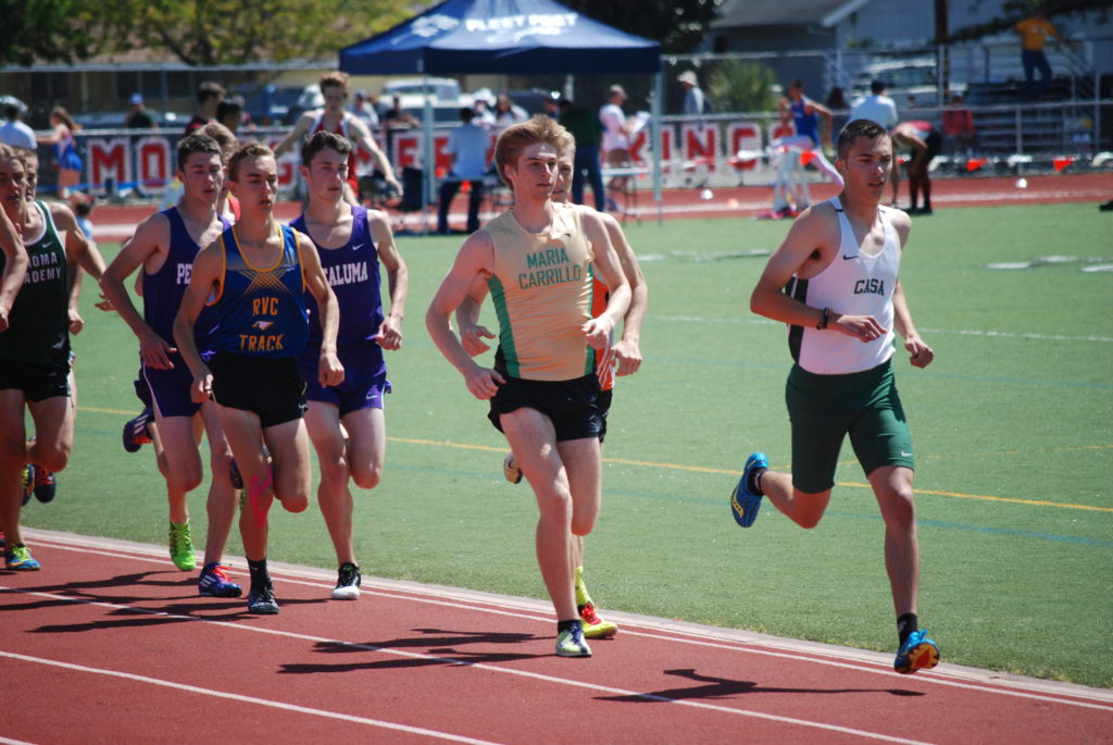 Athlete prepares for pole vault on a track with others watching.