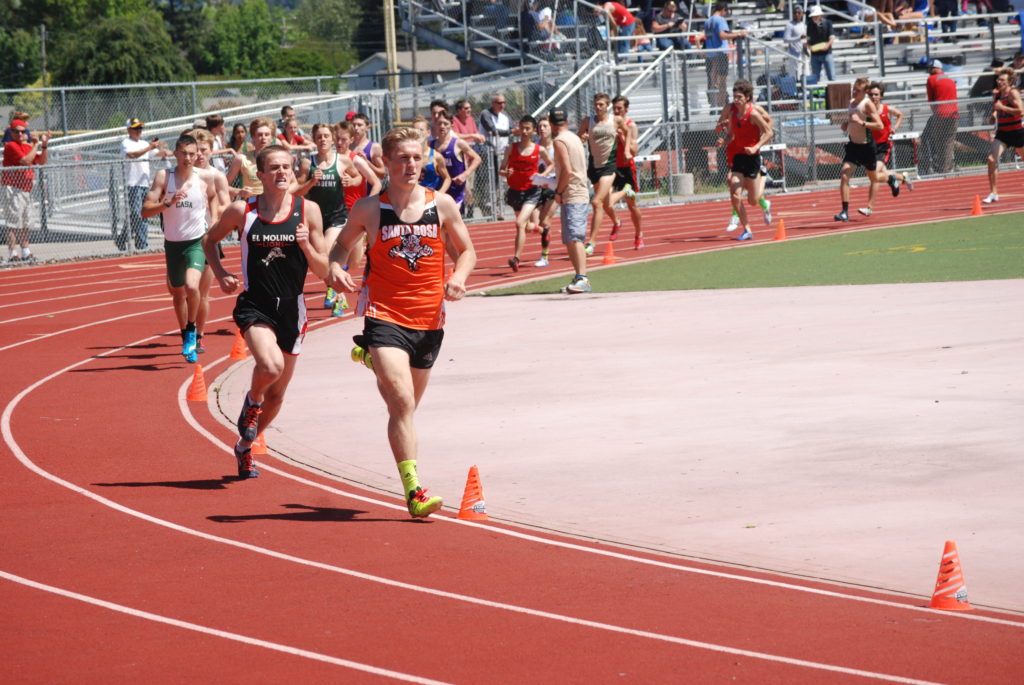 Athlete prepares for pole vault on a track with others watching.