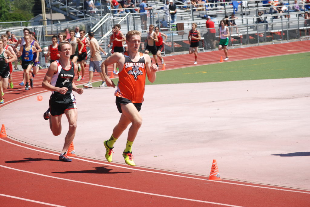 Athlete prepares for pole vault on a track with others watching.