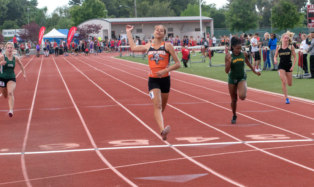 Athlete prepares for pole vault on a track with others watching.