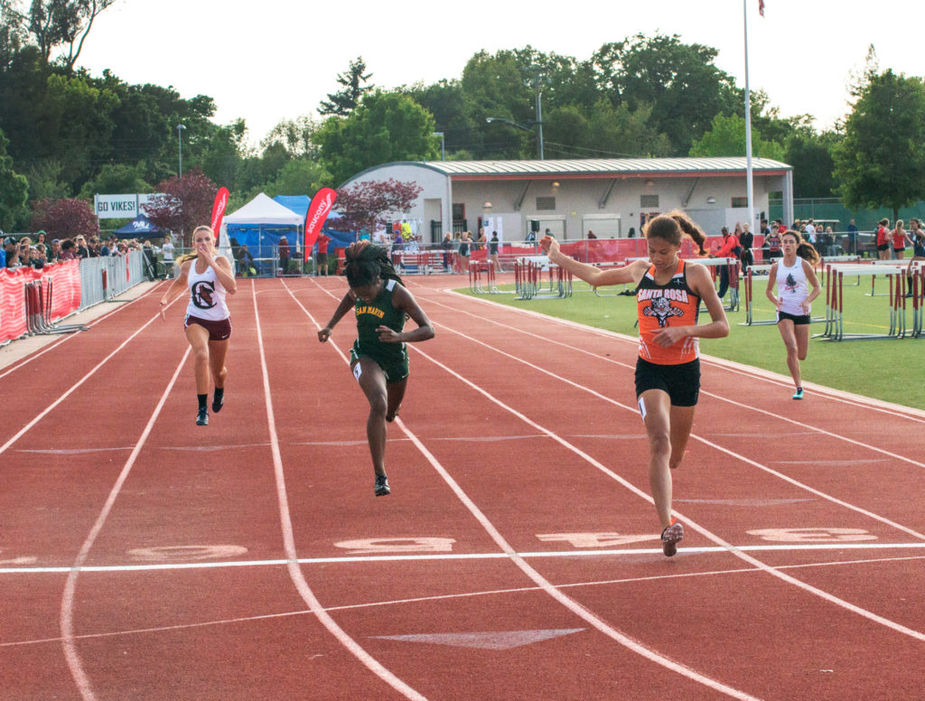 Athlete prepares for pole vault on a track with others watching.