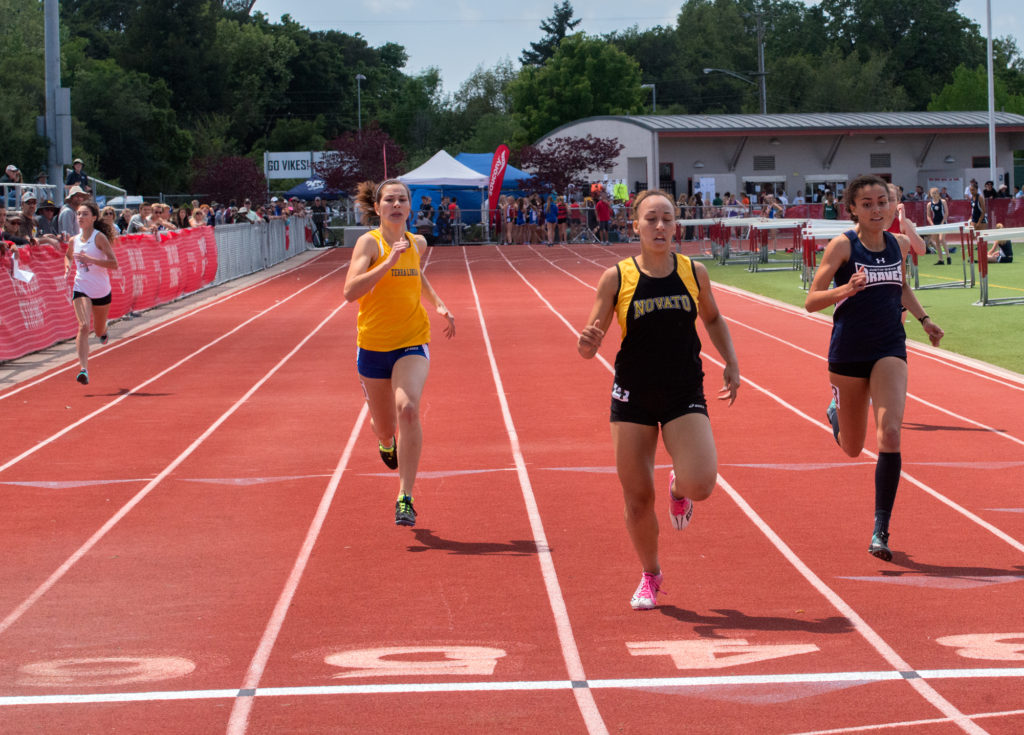 Athlete prepares for pole vault on a track with others watching.