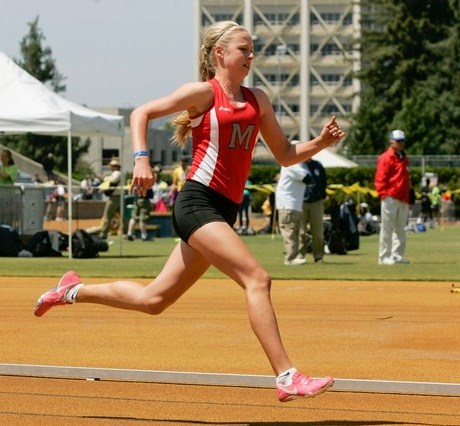 Athlete prepares for pole vault on a track with others watching.