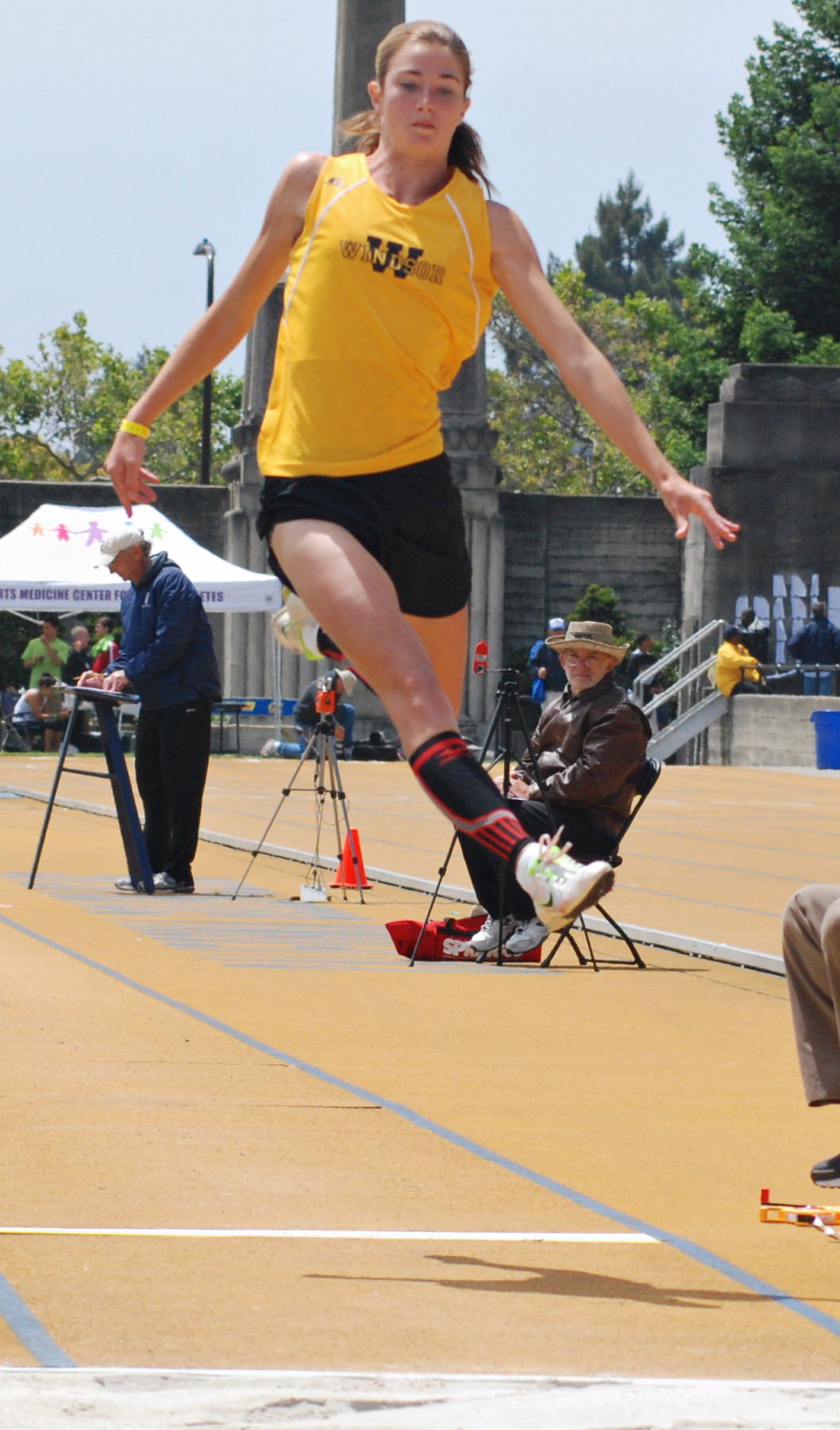 Athlete prepares for pole vault on a track with others watching.