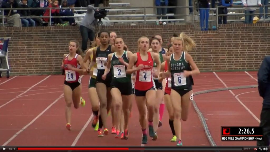 Athlete prepares for pole vault on a track with others watching.