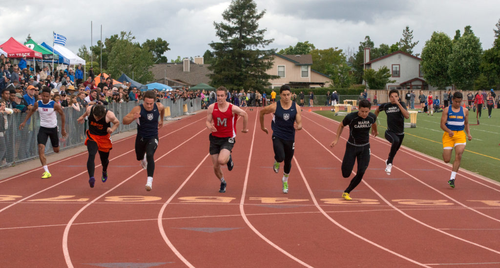 Athlete prepares for pole vault on a track with others watching.