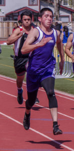 Athlete prepares for pole vault on a track with others watching.