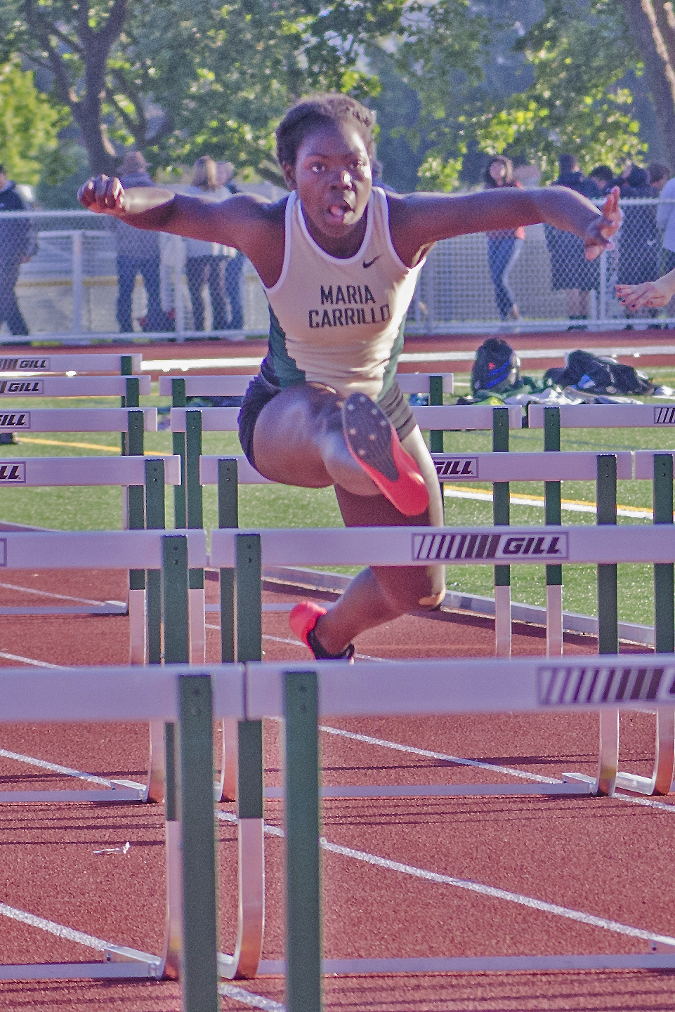 Athlete prepares for pole vault on a track with others watching.