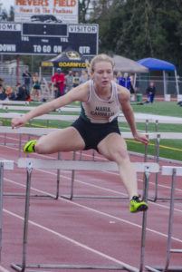 Athlete prepares for pole vault on a track with others watching.