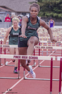 Athlete prepares for pole vault on a track with others watching.
