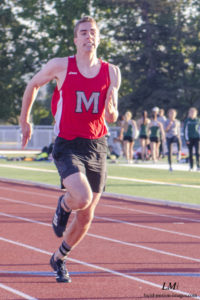 Athlete prepares for pole vault on a track with others watching.