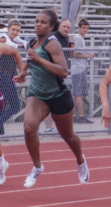 Athlete prepares for pole vault on a track with others watching.