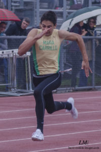 Athlete prepares for pole vault on a track with others watching.