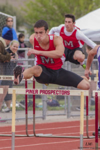 Athlete prepares for pole vault on a track with others watching.
