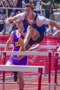 Athlete prepares for pole vault on a track with others watching.