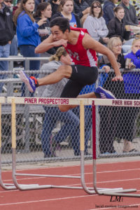 Athlete prepares for pole vault on a track with others watching.