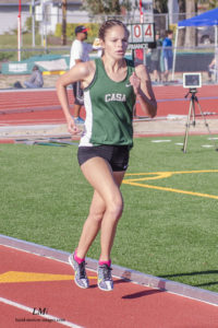 Athlete prepares for pole vault on a track with others watching.